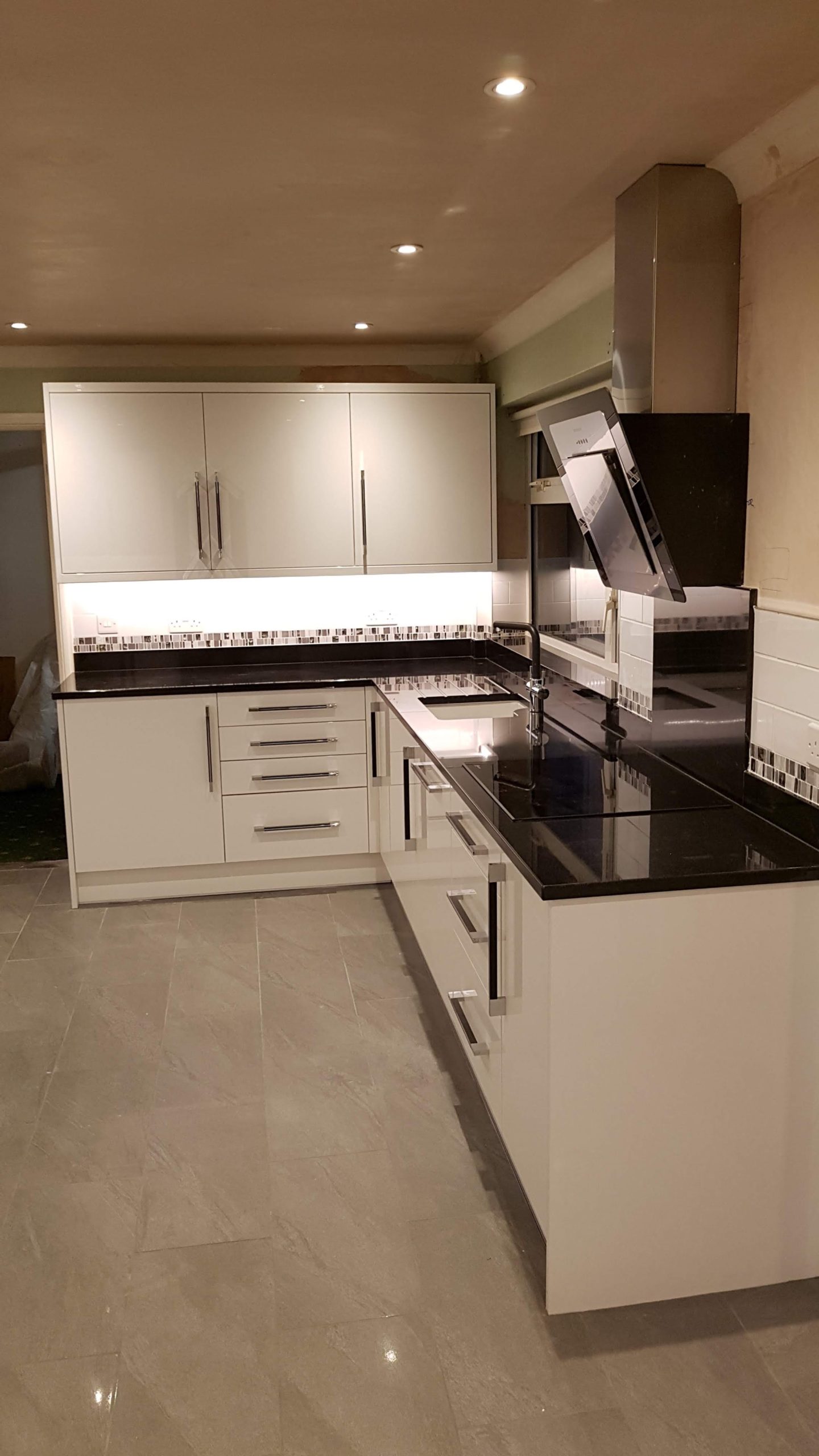 L shaped kitchen with white units and black worktops