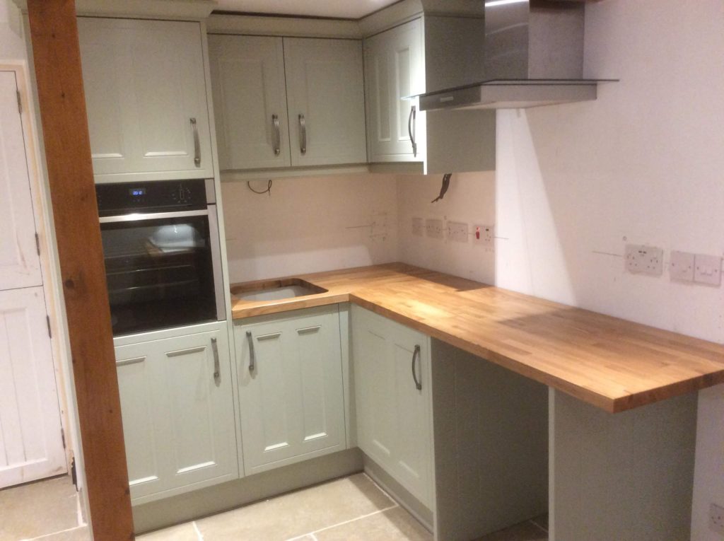 Compact light green Shaker Kitchen with solid oak worktops