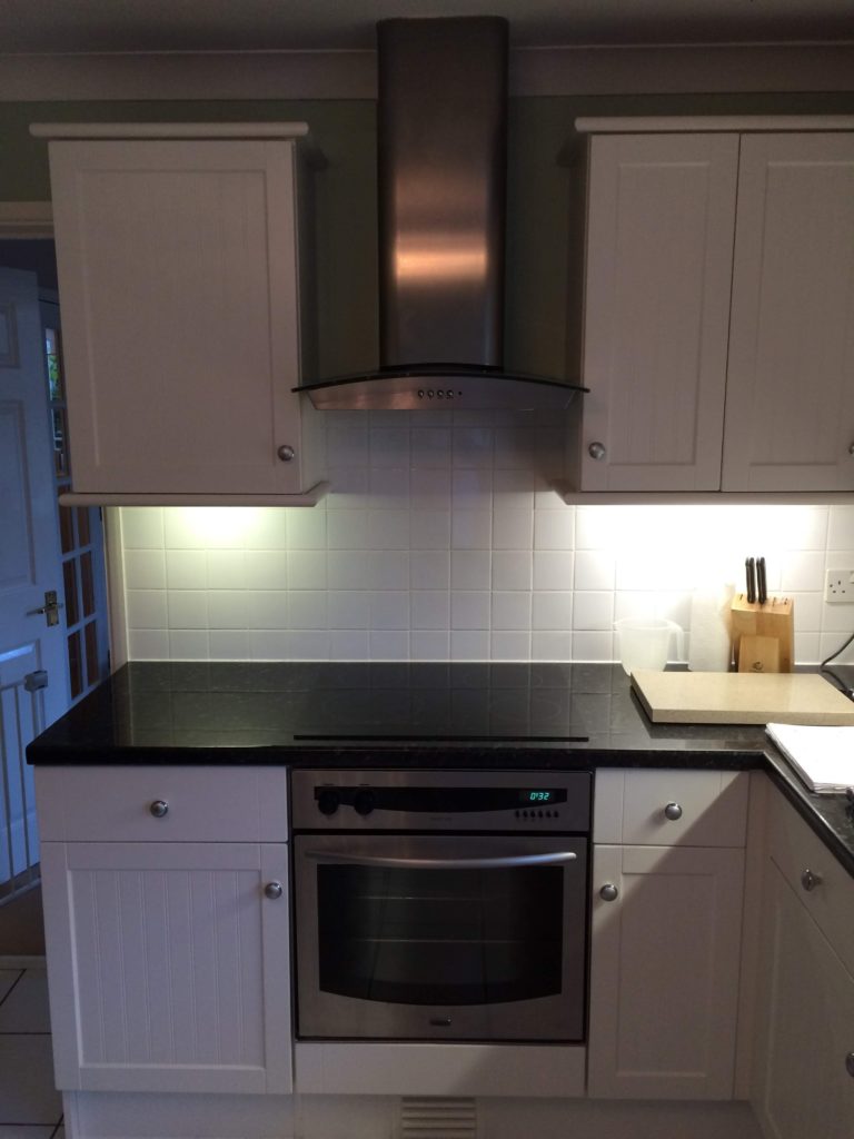 White shaker kitchen with single oven and extractor fan & underlighting
