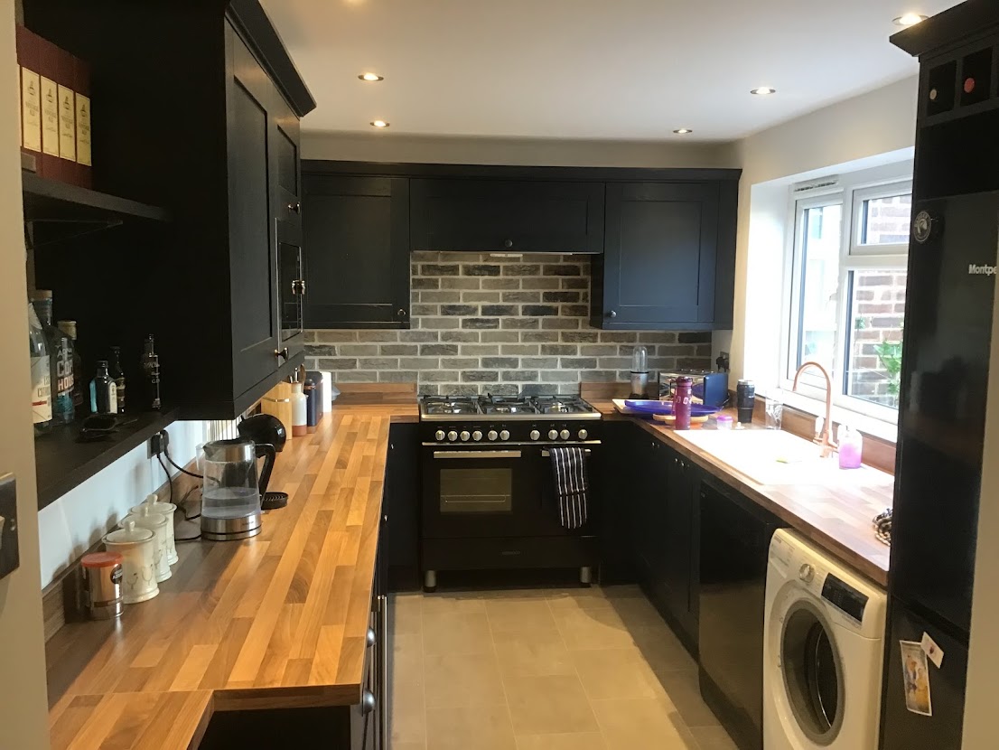 Dark kitchen units with brick wall feature