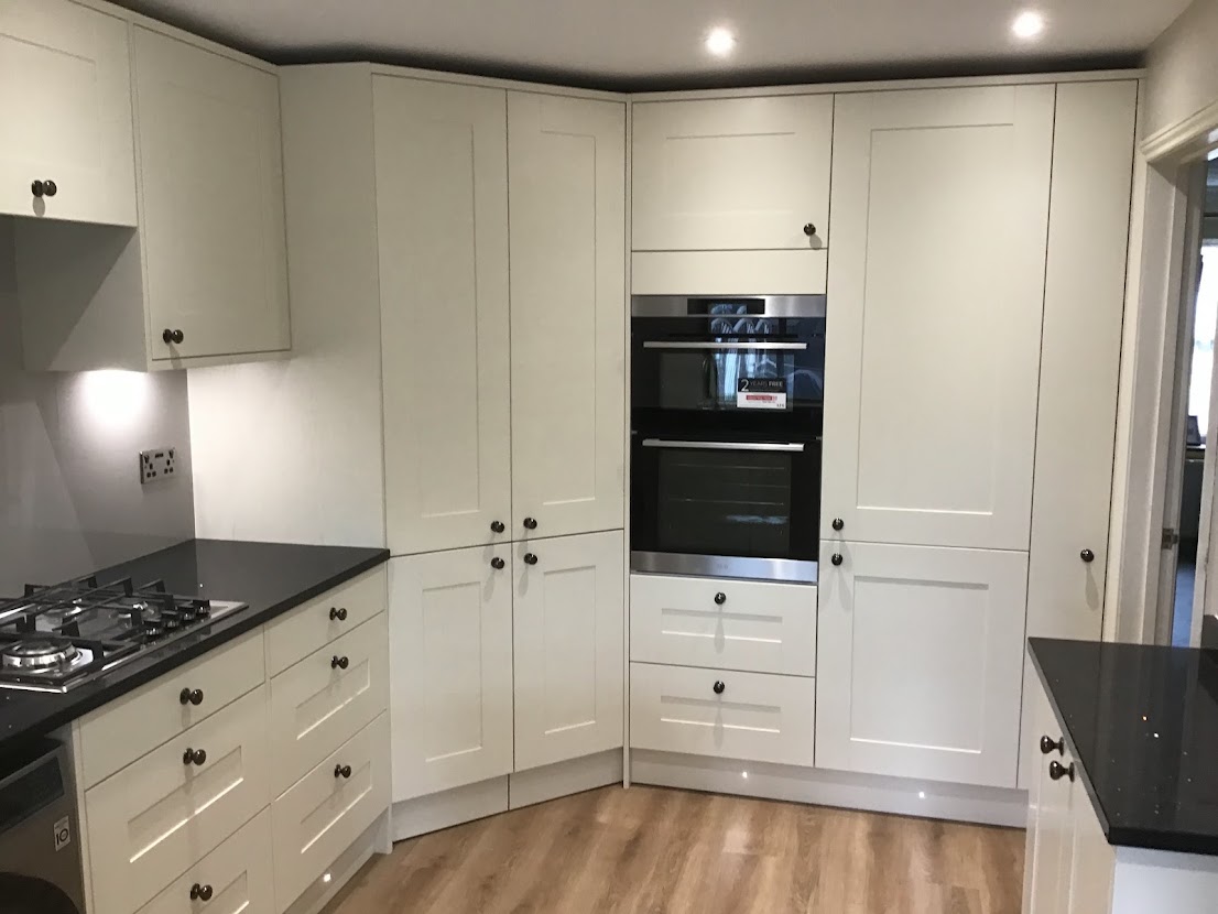 White angled corner units, black worktops and round handles